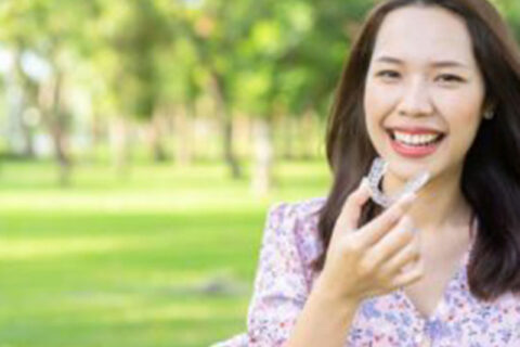 woman smiling with invislign in hand